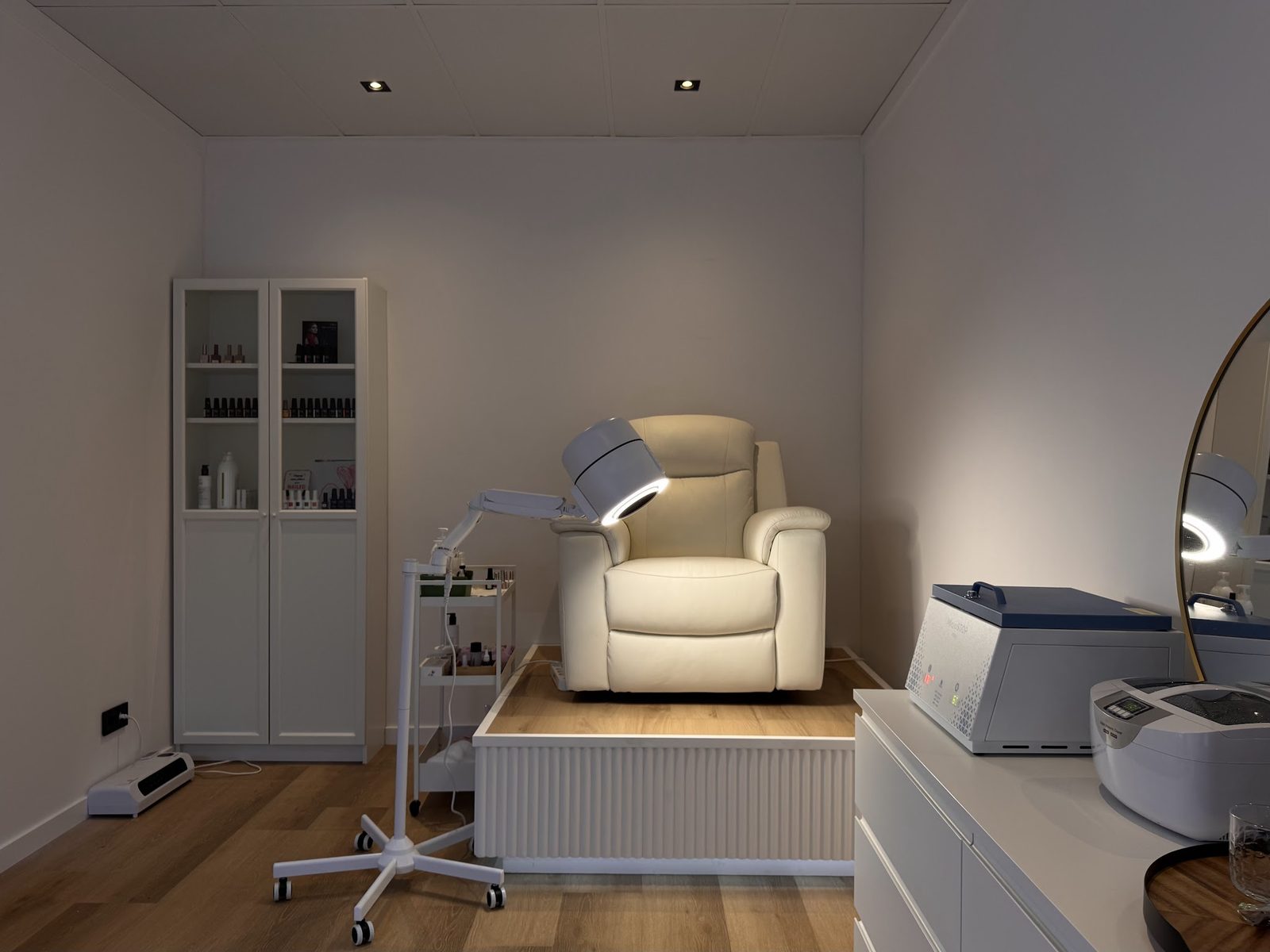 De pedicureruimte met een crèmekleurige behandelstoel, een witte kast en de apparatuur